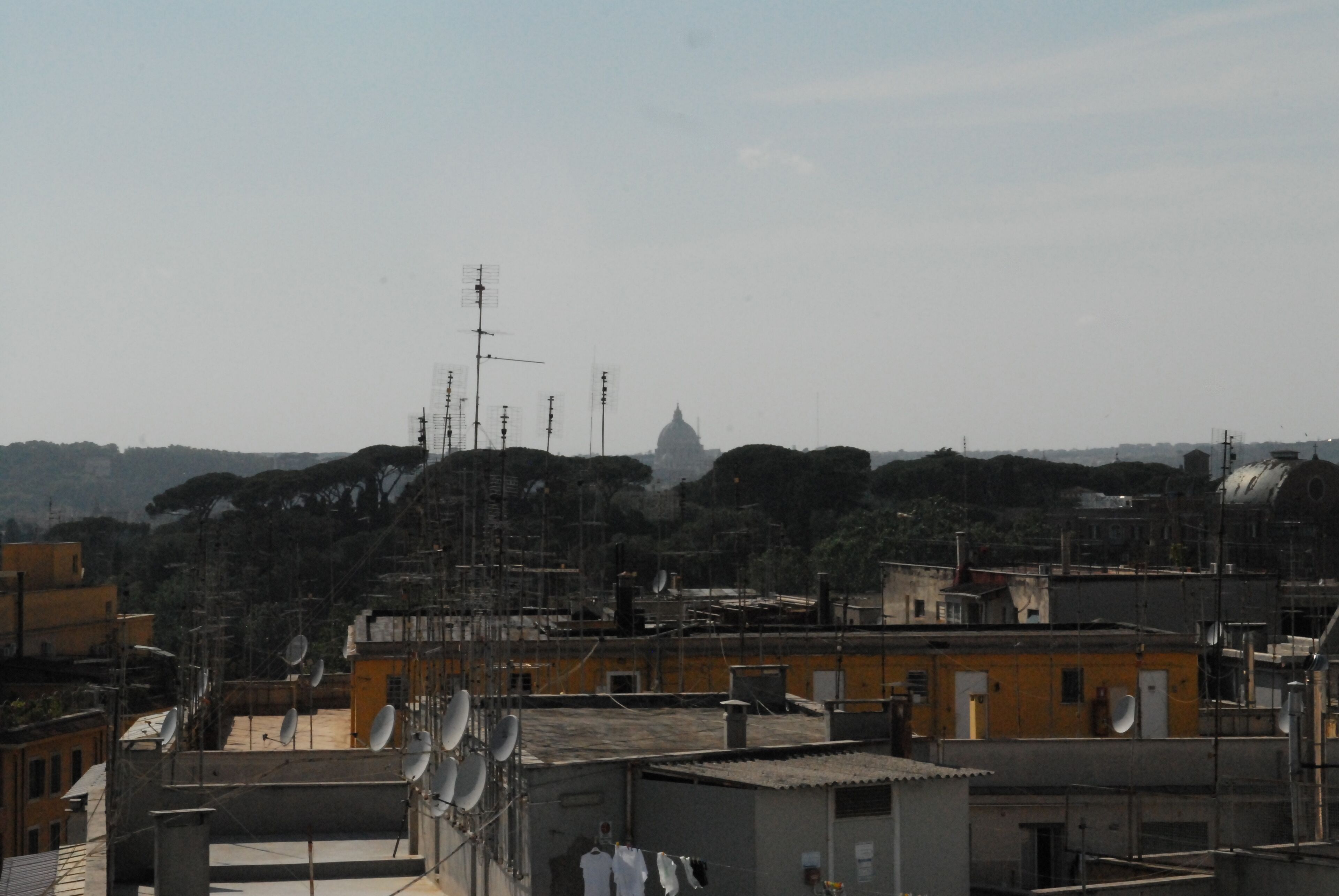 Une vue urbaine avec un imposant dôme visible au loin, entouré d’immeubles résidentiels dotés d’antennes paraboliques.