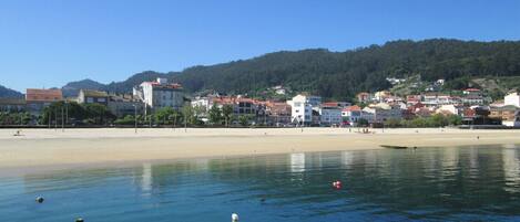 A coastal town with a sandy beach and buildings in the background.