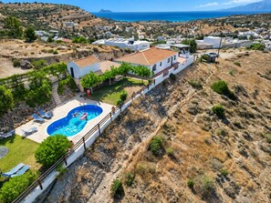 A residential area with a swimming pool, white houses, and a view of the sea. - Villa with sea and mountain views, private pool and large garden (Pitsidia)