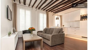 A modern living room with a sofa, coffee table, and a small side table with a vase of flowers.