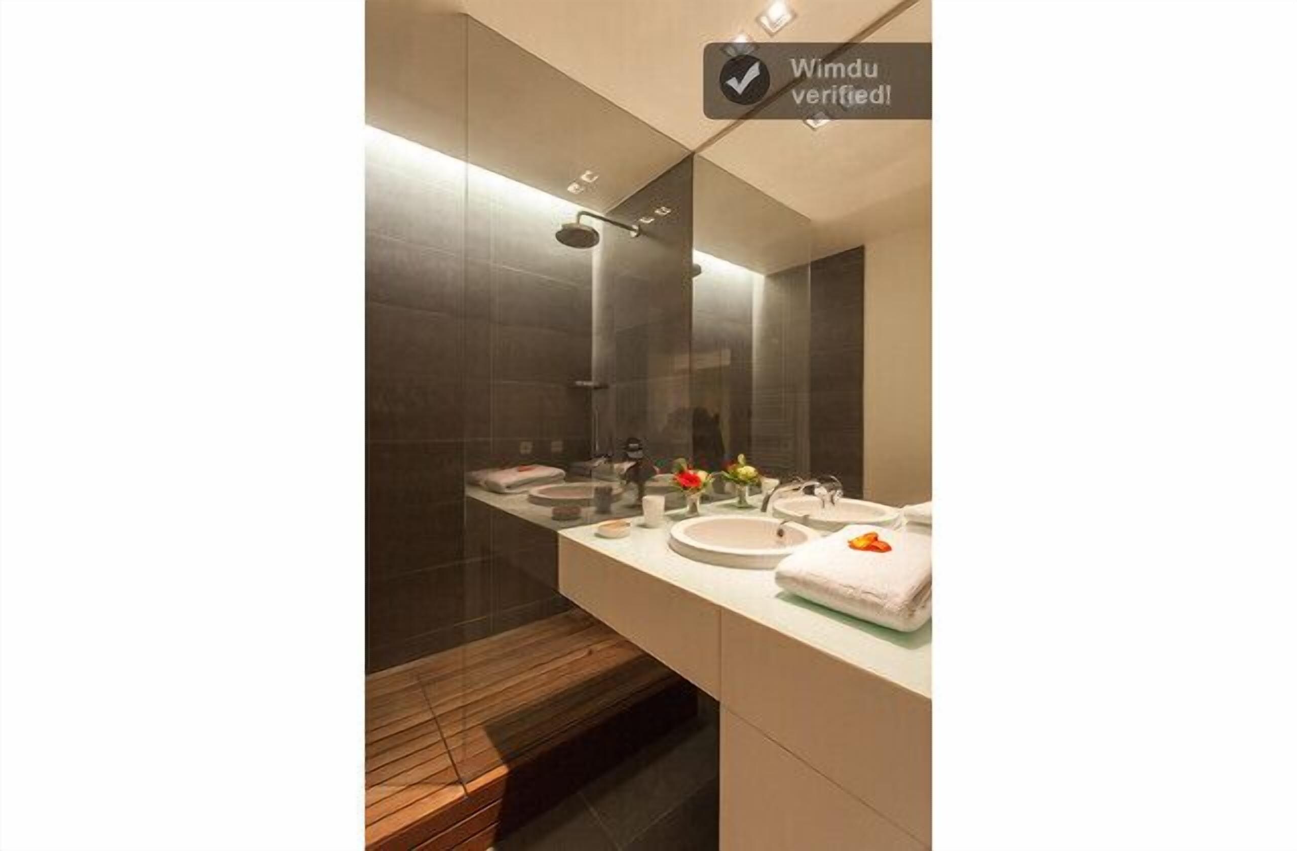 A modern bathroom with a glass shower enclosure, a vanity with two sinks, and a large mirror.