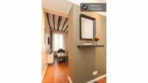 A hallway with a wooden floor, a reception desk, a mirror, and a sign that reads "Windu verified!"