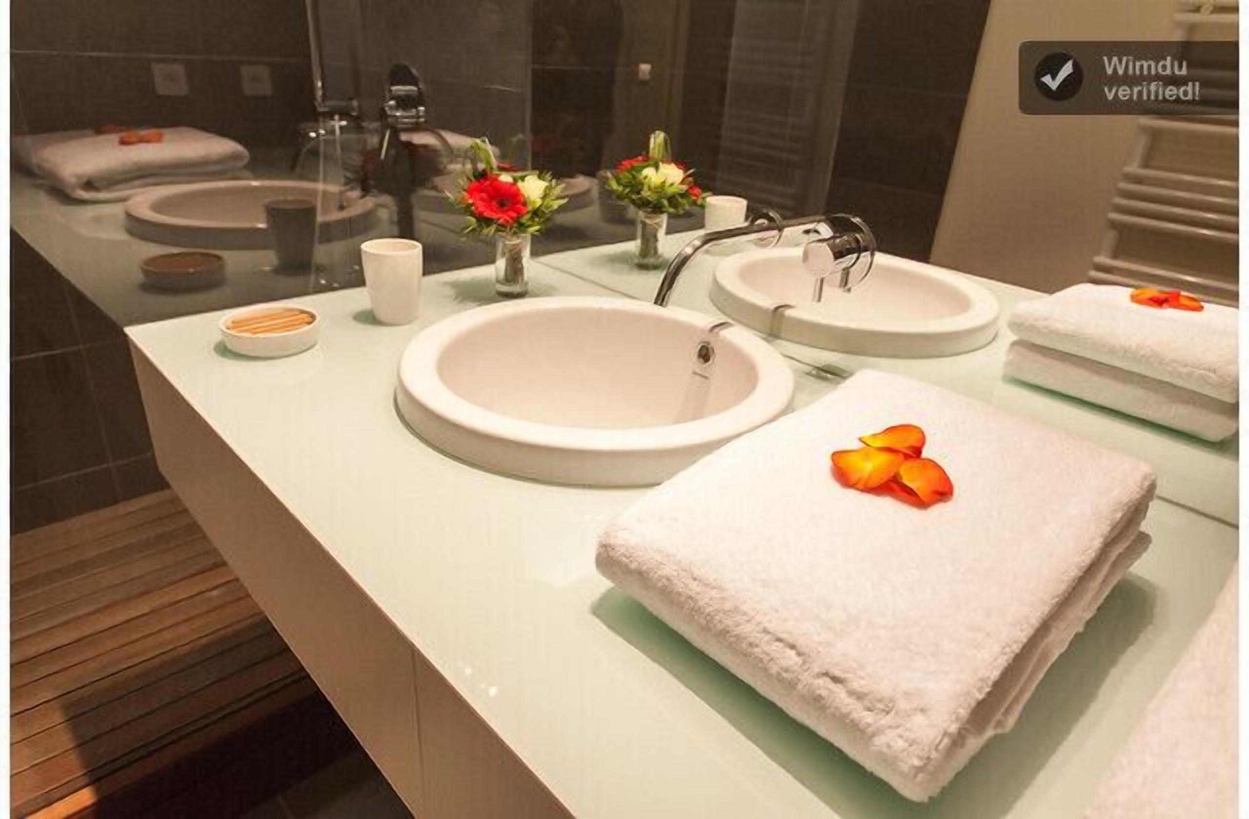A modern bathroom with two sinks, a mirror, and a towel with a flower.