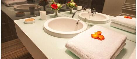 A modern bathroom with two sinks, a mirror, and a towel with a flower.