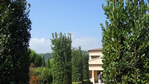 A paved pathway leading to a building with a tiled roof, surrounded by well-maintained hedges and greenery. - Penthouse. 4 pers. Private Solarium Terrace 105m2, pool 12 m by 6 (Saint-Paul-De-Vence)