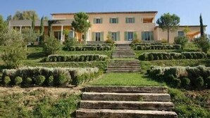 A building with a symmetrical facade, a central staircase leading to a door, and a well-maintained garden with hedges and trees. - Penthouse. 4 pers. Private Solarium Terrace 105m2, pool 12 m by 6 (Saint-Paul-De-Vence)