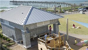 A playground with a slide and climbing structures, a covered seating area, and a view of the ocean. - 9/19-26 WOW SALE! Oceanfront House, 4-7 Night Stay, WEEKLY DEAL, Walk to Pier! (Kure Beach)