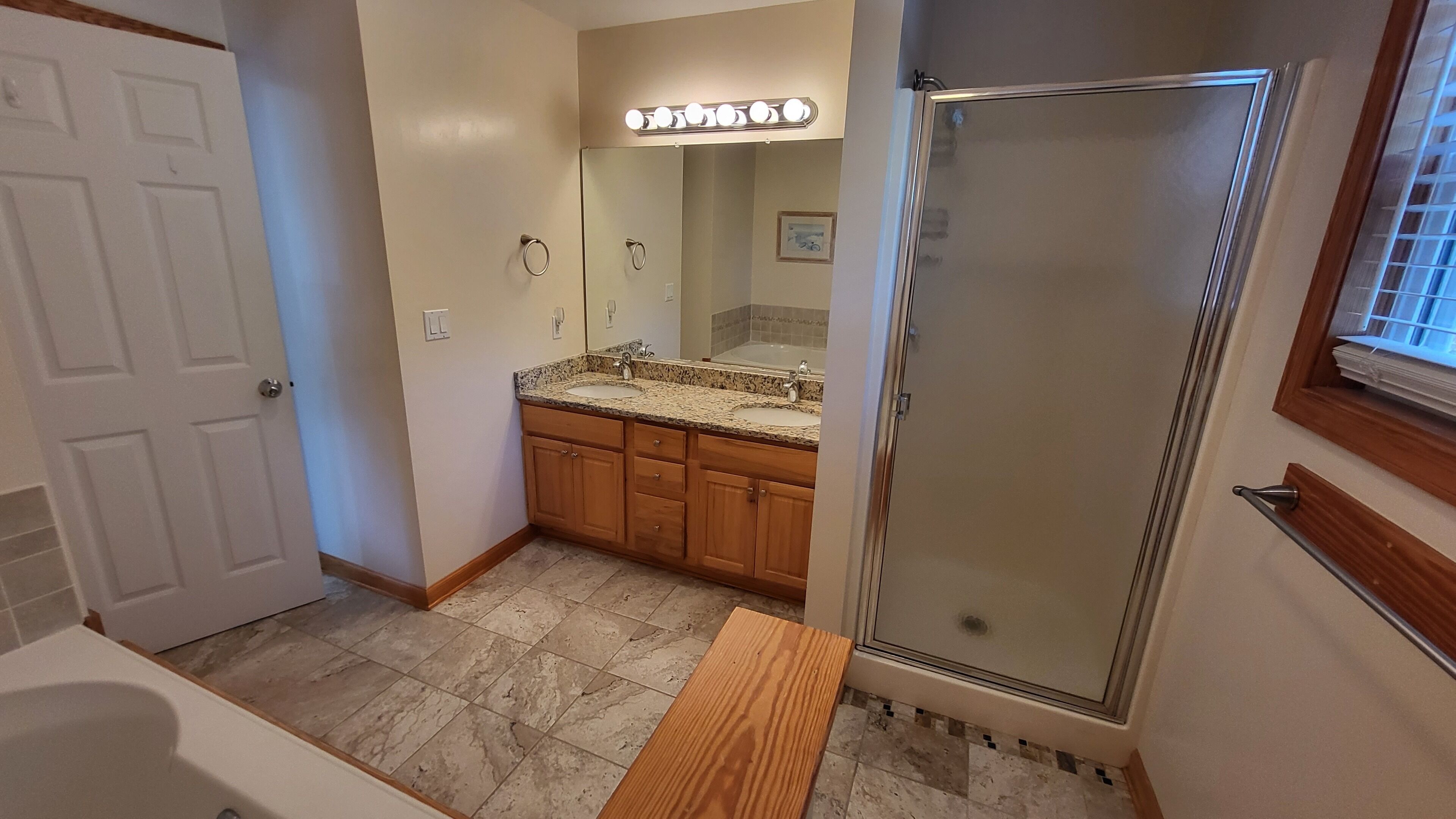 A bathroom with a shower, double sink vanity, and a mirror above the sink.