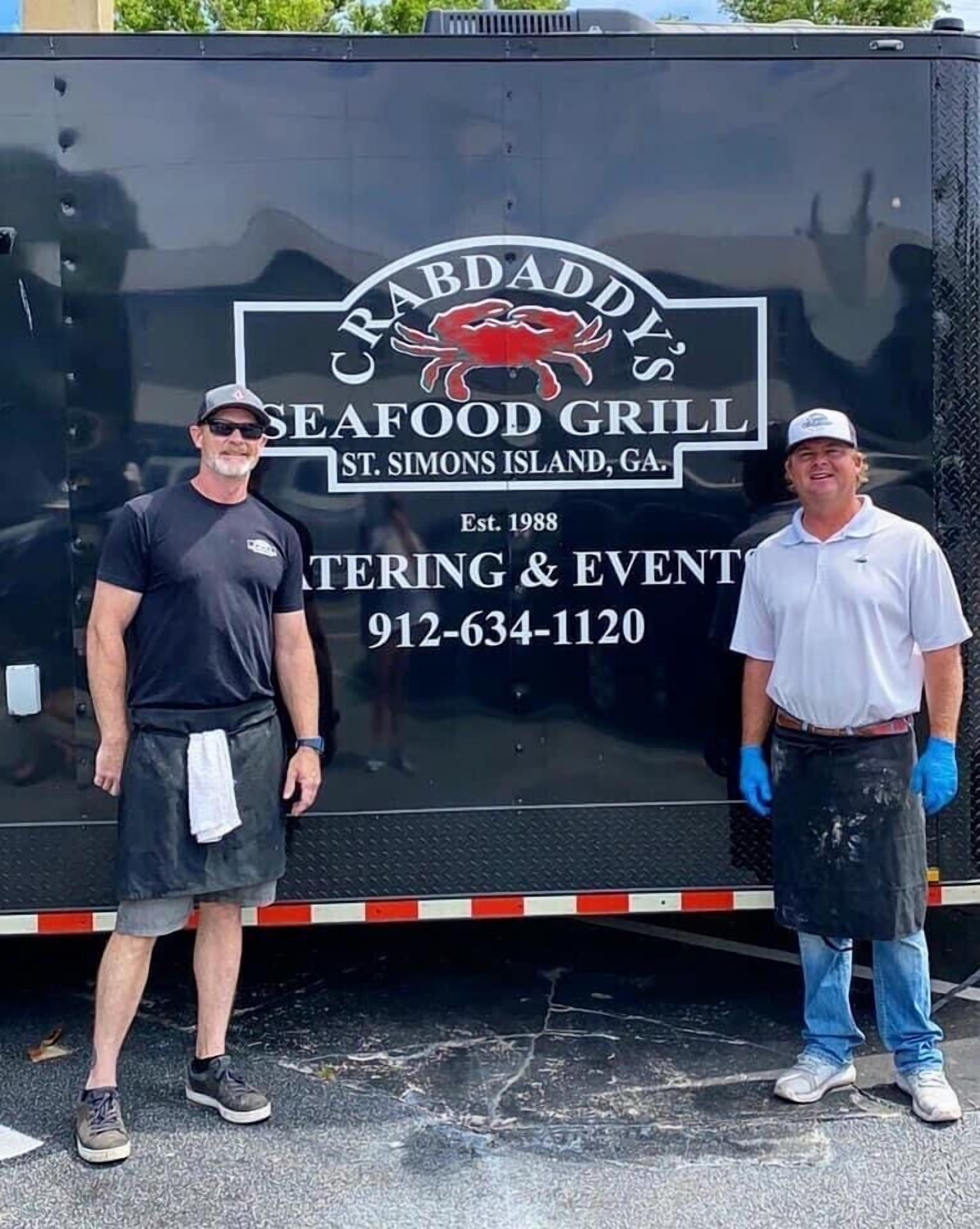 Ein großer, schwarzer Lastwagen mit der Werbung 'Crab Daddy's Seafood Grill' und Kontaktangaben.