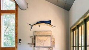 En restaurang med träbord och träbänkar, en stor fisk som hänger på väggen och en utsikt genom stora fönster.