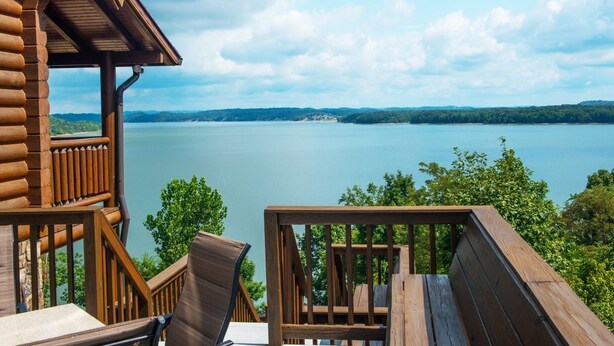 Eine Holzterrasse mit Blick auf einen See und sanfte Hügel in der Ferne.