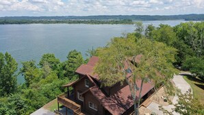 Eine Holzhütte mit Terrasse, die auf einen See mit Blick auf Bäume blickt.