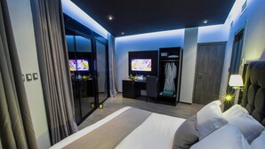Habitación de hotel moderna con una cama grande, un escritorio con computadora, un televisor y un armario.