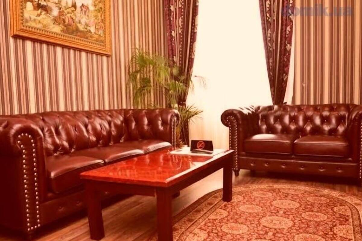 Une pièce avec deux canapés en cuir, une table basse en bois et un tapis à motifs.