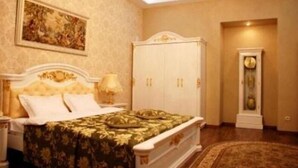 Un dormitorio con cama, mesita de noche, lámpara, armario y un cuadro en la pared.