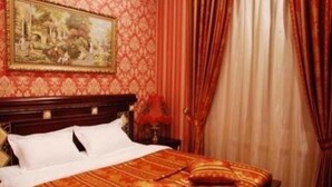 Habitación de hotel con cama, cabecero, un cuadro en la pared y cortinas.