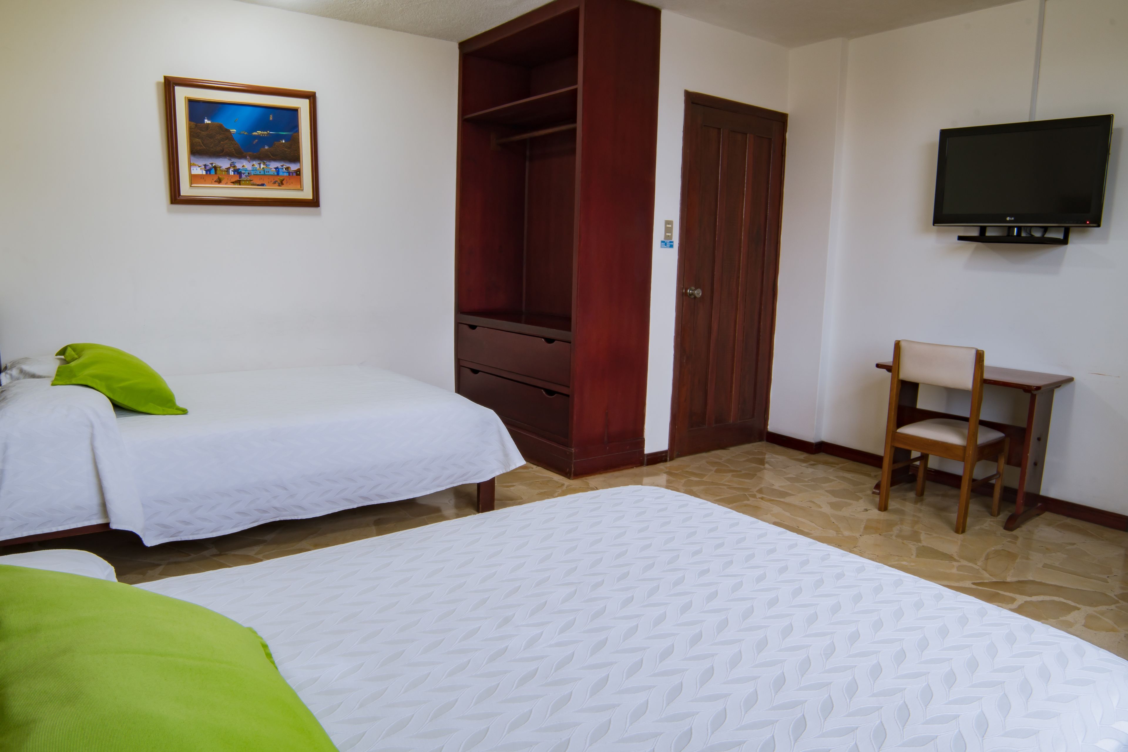 Una camera d'albergo con due letti, un armadio in legno, una televisione e un quadro appeso al muro.
