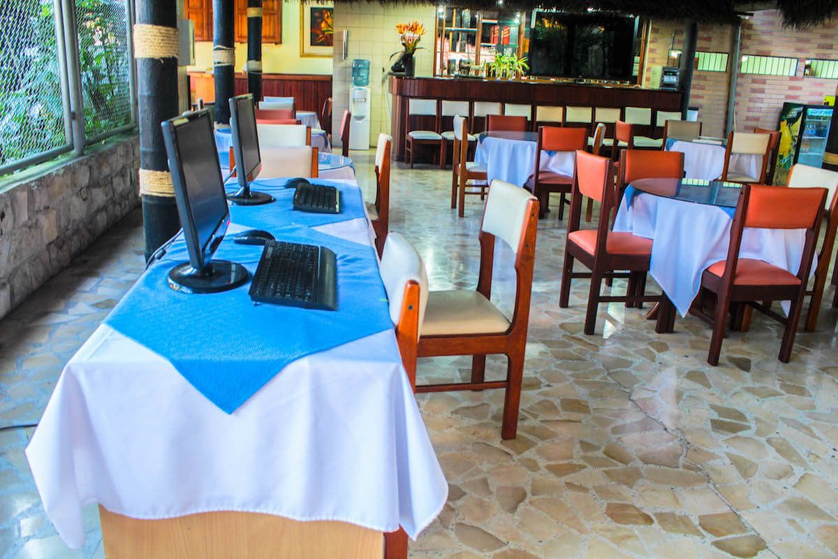 A restaurant with outdoor seating, tables covered with blue and white tablecloths, and wooden chairs.