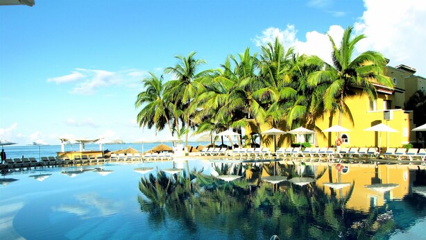 Una piscina al aire libre, sombrillas, sillones reclinables de piscina