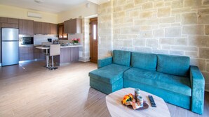 A modern kitchen with built-in appliances, a stone accent wall, and a teal sofa in a living area. - Villa Katerina (Chania)