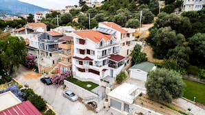 Un edificio residencial de varios pisos con balcones, un garaje y un pequeño jardín.