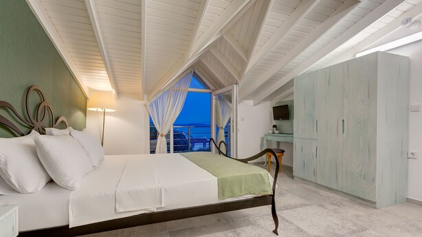 Un dormitorio con cama, mesita de noche, armario y vistas al exterior.