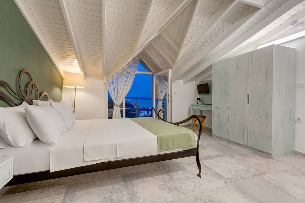 A bedroom with a bed, a nightstand, a wardrobe, and a view of the outside.