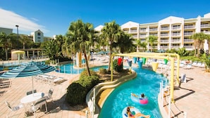 A pool area with lounge chairs, umbrellas, and a water slide. - Cape canaveral beach resort (Cape Canaveral)