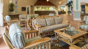 A spacious lobby with wicker furniture, a reception desk, and a large window. - Cape canaveral beach resort (Cape Canaveral)