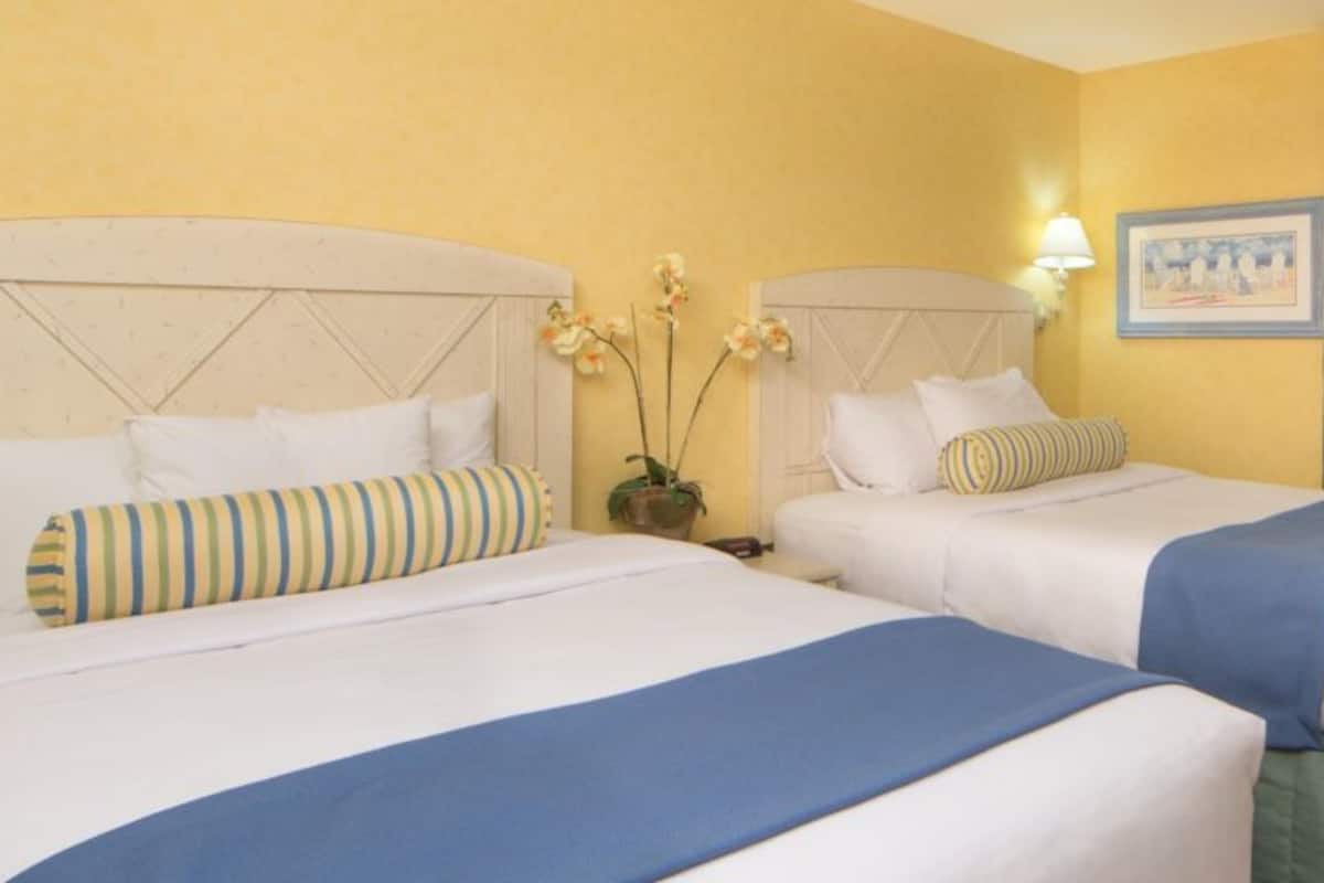 A hotel room with two beds, a television, and a desk.