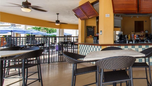 An outdoor cafe with tables and chairs, a counter with a coffee machine, and a checkered wall. - Cape canaveral beach resort (Cape Canaveral)