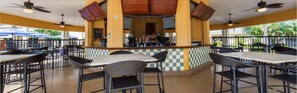 An outdoor cafe with tables and chairs, a counter with a coffee machine, and a checkered wall. - Cape canaveral beach resort (Cape Canaveral)
