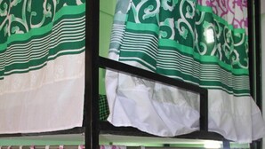 Camera con letto a castello, tende verdi e bianche a motivi, parete verde e copripiumino bianco.