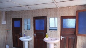 Un bagno con due lavandini, porte in legno e un secchio blu.