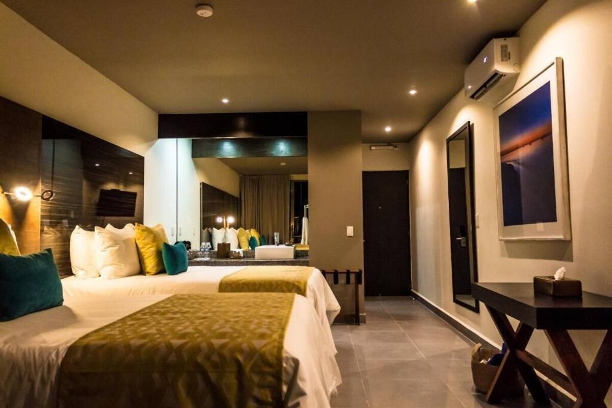 Een hotelkamer met twee bedden, een bureau, een spiegel en een airconditioning.