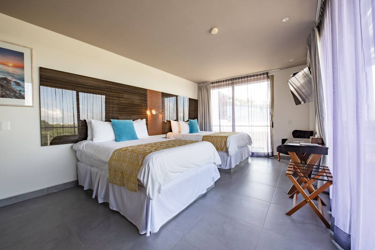 Een moderne hotelkamer met twee bedden, een flatscreen televisie, een bureau en een groot raam.