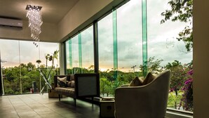 Uma sala de estar moderna com uma janela grande, um sofá, uma poltrona e um lustre decorativo.