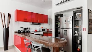 Une cuisine moderne avec des meubles rouges, un plan de travail en granit, des appareils électroménagers en acier inoxydable et un coin bar avec des tabourets.