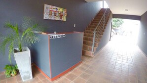 A reception desk with a sign, a staircase, and a bulletin board on the wall. - Islas De Arena (Colon)