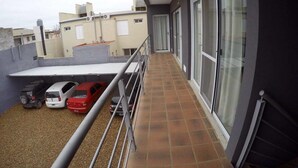 A balcony with a metal railing, a tiled floor, and a view of neighboring buildings. - Islas De Arena (Colon)