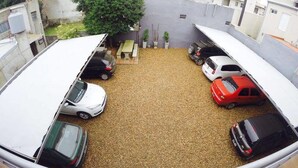 A parking area with multiple cars and a small garden with a bench and potted plants. - Islas De Arena (Colon)