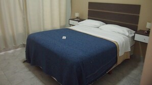 A hotel room with a bed, a nightstand, a lamp, and a curtain. - Islas De Arena (Colon)
