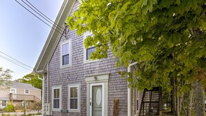 Une maison à deux étages avec une porte d’entrée, des fenêtres et un petit porche.