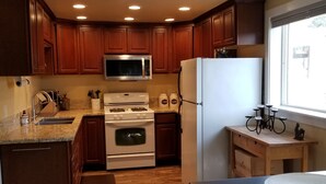 Una cocina con armarios de madera, microondas, estufa y refrigerador.