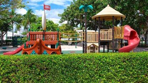 Un parque infantil con un tobogán rojo, una estructura para escalar y un pabellón.