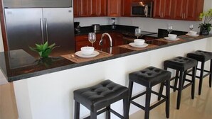 Una cocina moderna con armarios de madera, un refrigerador de acero inoxidable, un microondas y una barra con taburetes.