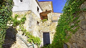 A narrow alleyway with stone buildings, one with a black door and a small window, surrounded by greenery. - Villa Fragola beautiful house whit pool and panoramic view (Motovun)