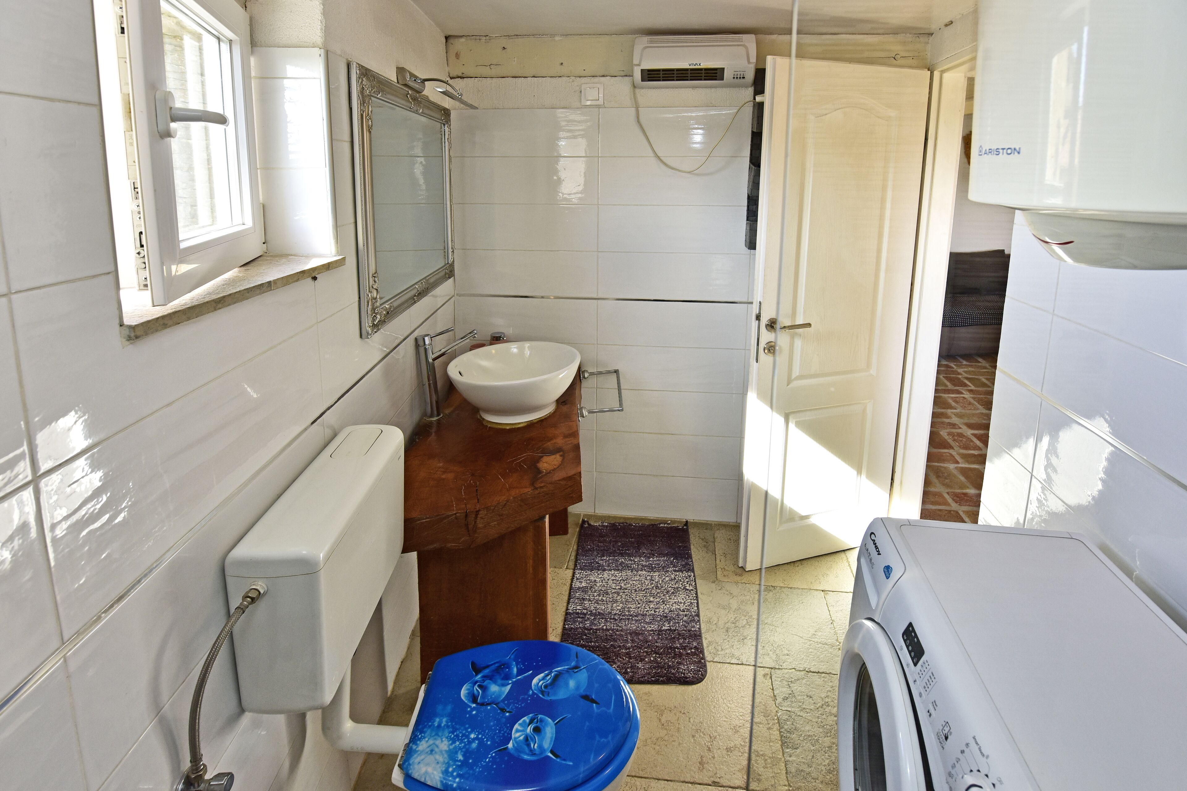 Un bagno piccolo con lavandino bianco, uno specchio, un water e una lavatrice.