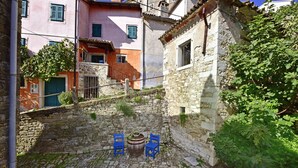 A courtyard with stone flooring, two blue chairs, and a rustic barrel. - Villa Fragola beautiful house whit pool and panoramic view (Motovun)