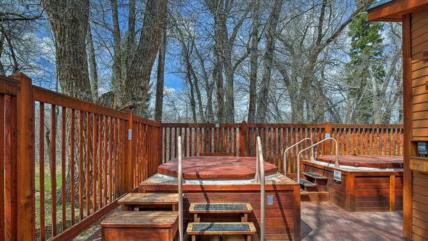 A wooden deck with hot tubs and steps leading to a covered area, surrounded by trees. - Cozy Driggs Condo w/ Hot Tub & Ski Shuttle Service (Driggs)
